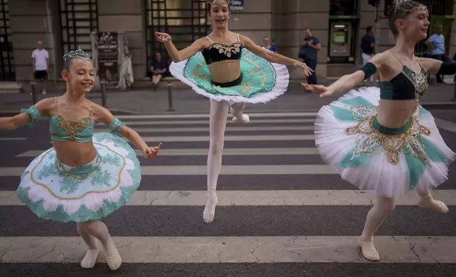 Dora, 10, left, Irina, 11, center, and Sandra, 12, of the Romanian National Opera's Ballet Studio, perform outside the National History Museum of Romania during Dance Night, an event featuring a wide variety of dance styles performed on the Calea Victoriei avenue in Bucharest, Romania, Saturday, Aug. 23, 2025. (AP Photo/Andreea Alexandru)
