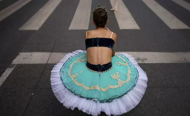 Irina, 11, of the Romanian National Opera's Ballet Studio, takes pictures of her colleagues after dancing outside the National History Museum of Romania during Dance Night, an event featuring a wide variety of dance styles performed on the Calea Victoriei avenue in Bucharest, Romania, Saturday, Aug. 23, 2025. (AP Photo/Andreea Alexandru)