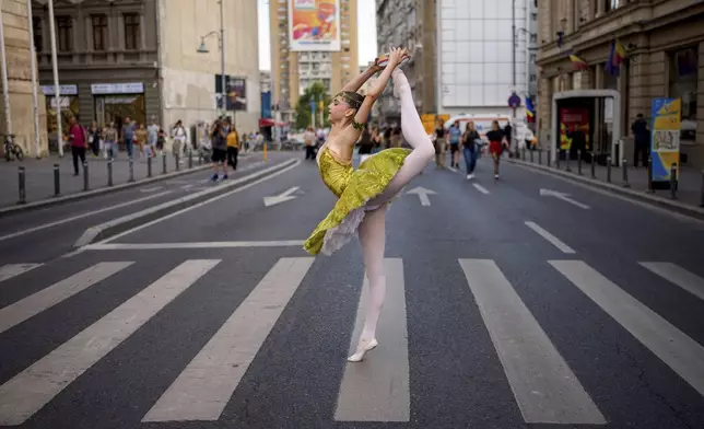 Daria Toma, 15, of the Romanian National Opera's Ballet Studio strikes a pose outside the National History Museum of Romania during Dance Night, an event featuring a wide variety of dance styles performed on the Calea Victoriei avenue in Bucharest, Romania, Saturday, Aug. 23, 2025. (AP Photo/Andreea Alexandru)