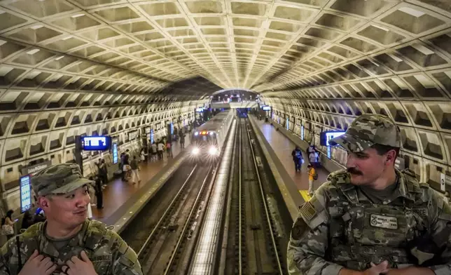 A train passes through as District of Columbia National Guardsmen patrol inside the Gallery Place-Chinatown Metro Station, Sunday, Aug. 17, 2025, in Washington. (AP Photo/Julia Demaree Nikhinson)
