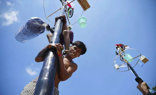 A participant reacts during a greased-pole climbing competition held to celebrate Indonesia's 80th Independence Day, at Ancol Beach in Jakarta, Indonesia, Sunday, Aug. 17, 2025. (AP Photo/Tatan Syuflana)