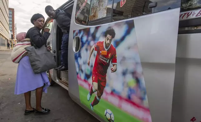 A woman boards a minibus taxi branded with an image of a Liverpool Football Club winger Mohamed Salah, in Harare, Zimbabwe, Sunday, Aug. 10, 2025. (AP Photo/Aaron Ufumeli)