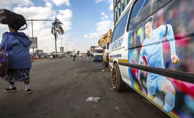 A woman walks past a minibus taxi with the Manchester Football Club player Phil Foden, in Harare, Zimbabwe, Sunday, Aug. 10, 2025. (AP Photo/Aaron Ufumeli)