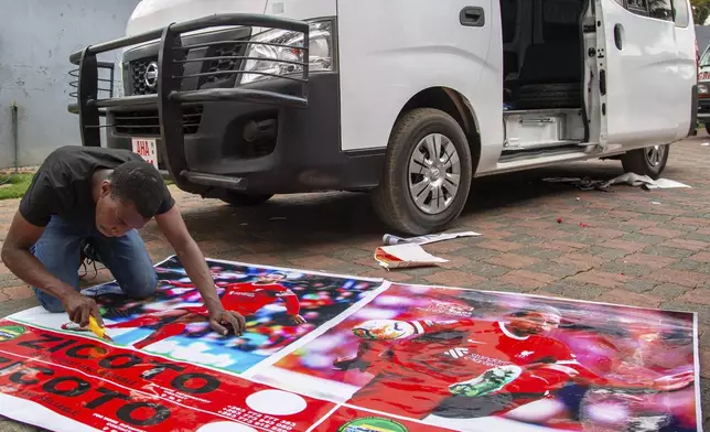 Brian Gondo prepares cuts off a graphic image of Liverpool Football Club captain Virgil Van Dyke to brand on a minibus taxi, in Harare, Zimbabwe, Sunday, Aug. 10, 2025. (AP Photo/Aaron Ufumeli)