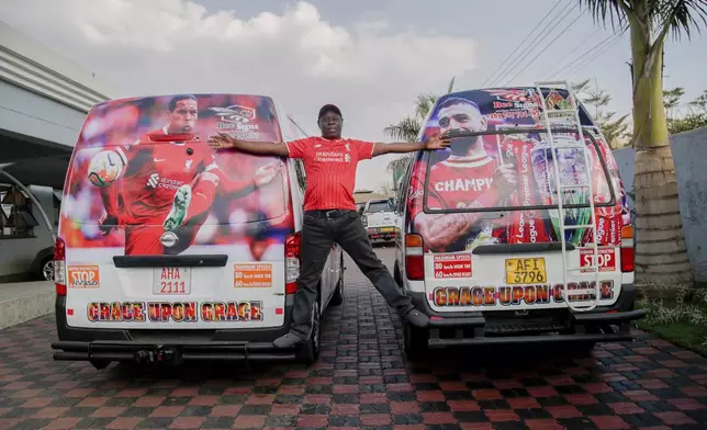 Justin Kisimusi, a minibus taxis operator and a Liverpool Football Club fan, poses with his vehicles following their branding, in Harare, Zimbabwe, Sunday, Aug. 10, 2025. (AP Photo/Aaron Ufumeli)