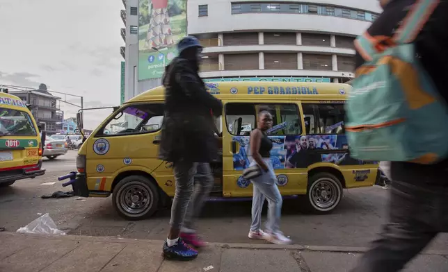 People walk past a minibus taxi branded with Manchester City Football Club player and head coach, in Harare, Zimbabwe, Sunday, Aug. 10, 2025. (AP Photo/Aaron Ufumeli)