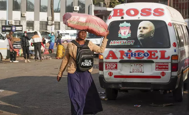 A woman walks past a minibus taxi branded with image of the Liverpool Football Club manager Arne Slot, in Harare, Zimbabwe, Sunday, Aug. 10, 2025. (AP Photo/Aaron Ufumeli)