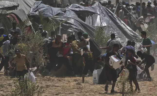 Palestinians rush to collect humanitarian aid packages from the United Arab Emirates, airdropped by parachutes into Deir al-Balah, in the central Gaza Strip, Tuesday, Aug. 19, 2025. (AP Photo/Abdel Kareem Hana)