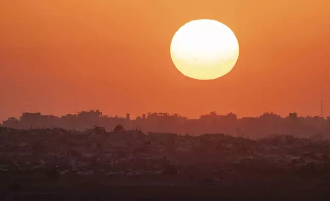 The sun sets behind buildings destroyed during Israeli ground and air operations in the Gaza Strip, as seen from southern Israel, Friday, Aug. 29, 2025. (AP Photo/Maya Levin)