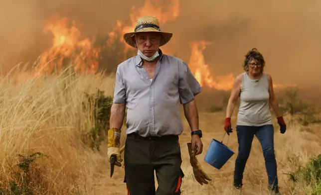 Local residents react in front of the fire during a wildfire in Santa Baia De Montes, northwestern Spain, Thursday, Aug. 14, 2025. (AP Photo/Lalo R. Villar)