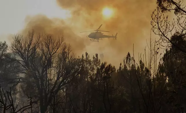 A helicopter drops water on a wildfire in Larouco, northwestern Spain, Wednesday, Aug. 13, 2025. (AP Photo/Lalo R. Villar)