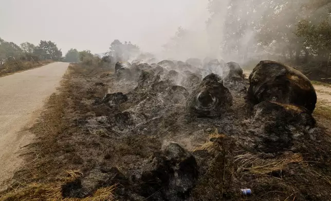 Bunred bale of straw are pictured during a forest fire in Pareisas, northwestern Spain, Wednesday, Aug. 13, 2025. (AP Photo/Lalo R. Villar)