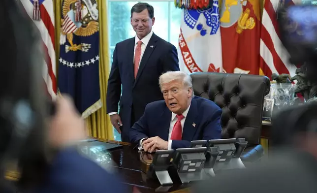 President Donald Trump speaks with reporters as Social Security Commissioner Frank Bisignano listens during an event in the Oval Office to mark the 90th anniversary of the Social Security Act, Thursday, Aug. 14, 2025, in Washington. (AP Photo/Alex Brandon)