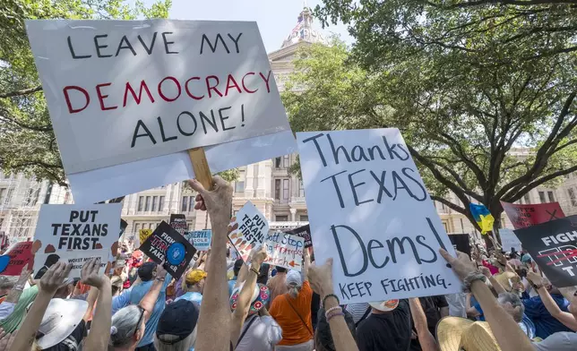 Protestors hold up signs during the Fight The Trump Takeover Rally held at the State Capitol, Saturday, Aug. 16, 2025, in Austin, Texas, to protest congressional redistricting efforts by Texas Republicans and President Donald Trump. (AP Photo/Rodolfo Gonzalez)