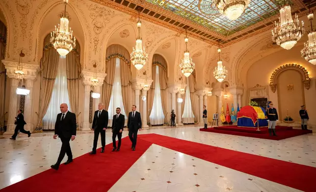 Romanian Prime Minister Ilie Bolojan, left, alongside members of his cabinet, leave after paying their respects at the coffin of the late Ion Iliescu, Romania's first freely elected president after the fall of communism in 1989, at the Cotroceni Presidential Palace, in Bucharest, Romania, Wednesday, Aug. 6, 2025.(AP Photo/Vadim Ghirda)