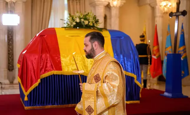 A priest performs a brief religious service next to the coffin of the late Ion Iliescu, Romania's first freely elected president after the fall of communism in 1989, at the Cotroceni Presidential Palace, in Bucharest, Romania, Wednesday, Aug. 6, 2025.(AP Photo/Vadim Ghirda)