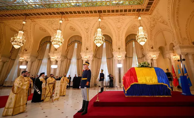 Priests perform a brief religious service next to the coffin of the late Ion Iliescu, Romania's first freely elected president after the fall of communism in 1989, at the Cotroceni Presidential Palace, in Bucharest, Romania, Wednesday, Aug. 6, 2025.(AP Photo/Vadim Ghirda)