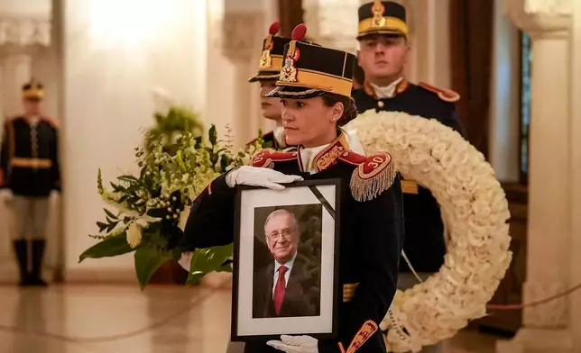 Honor guard soldiers carry a picture of the late Ion Iliescu, Romania's first freely elected president after the fall of communism in 1989, ahead of his coffin at the Cotroceni Presidential Palace, in Bucharest, Romania, Wednesday, Aug. 6, 2025.(AP Photo/Vadim Ghirda)