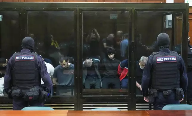 Suspects accused of involvement in a terror attack in the Crocus City Hall on March 22, 2024, sit in a glass cage prior to a hearing in the 2nd Western District Military Court in Moscow, Russia, Monday, Aug. 4, 2025. (AP Photo/Pavel Bednyakov)