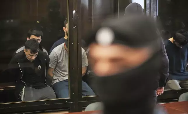 Suspects accused of involvement in a terror attack in the Crocus City Hall on March 22, 2024, sit in a glass cage prior to a hearing in the 2nd Western District Military Court in Moscow, Russia, Monday, Aug. 4, 2025. (AP Photo/Pavel Bednyakov)