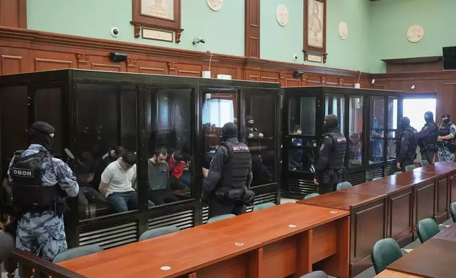 Suspects accused of involvement in a terror attack in the Crocus City Hall on March 22, 2024, sit in a glass cage prior to a hearing in the 2nd Western District Military Court in Moscow, Russia, Monday, Aug. 4, 2025. (AP Photo/Pavel Bednyakov)