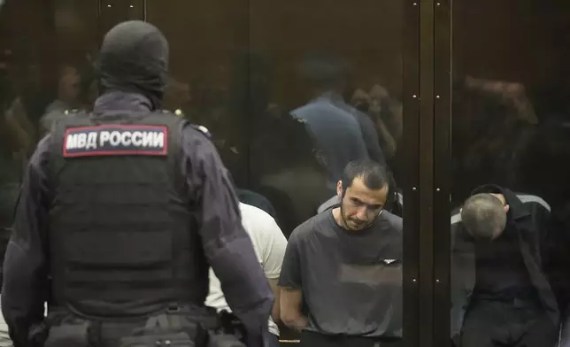Suspects accused of involvement in a terror attack in the Crocus City Hall on March 22, 2024, sit in a glass cage prior to a hearing in the 2nd Western District Military Court in Moscow, Russia, Monday, Aug. 4, 2025. (AP Photo/Pavel Bednyakov)