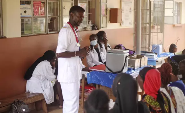 A health worker talks to patients at Wakiso Health Centre IV in Kampala, Wakiso, Tuesday, July 22, 2025. (AP Photo/Patrick Onen)
