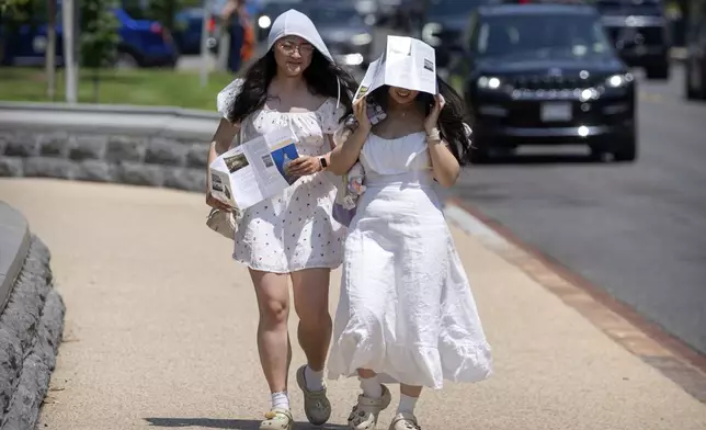 FILE - Visitors use brochures to shield themselves from the sun as they walk near the U.S. Capitol on an unseasonably hot day, June 24, 2025, in Washington. (AP Photo/Mark Schiefelbein, File)