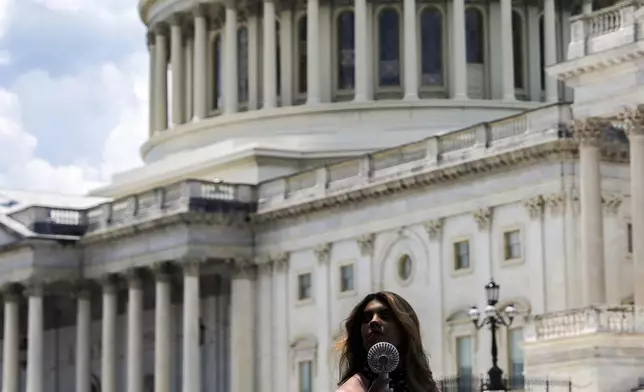 FILE - A woman uses a portable fan to cool down June 25, 2025, outside the U.S. Capitol in Washington. (AP Photo/Julia Demaree Nikhinson, File)