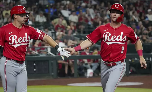 Cincinnati Reds' Santiago Espinal, right, slaps hands with Matt McLain (9) after McLain scored against the Arizona Diamondbacks during the eighth inning of a baseball game Saturday, Aug. 23, 2025, in Phoenix. (AP Photo/Darryl Webb)