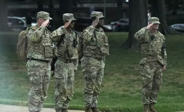 National Guard soldiers salute as the motorcade carrying President Donald Trump, passes by near the White House, Thursday, Aug. 21, 2025, in Washington. (AP Photo/Jacquelyn Martin)