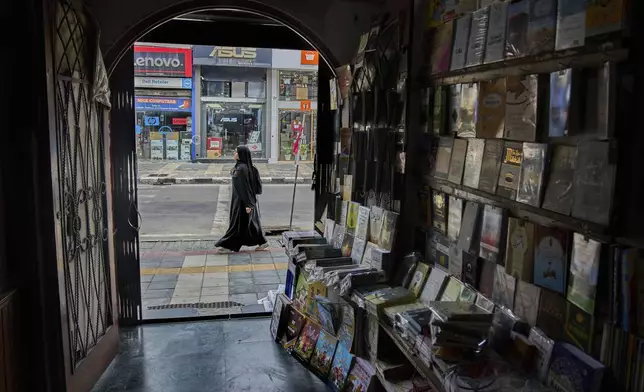 A Kashmir woman walks past a book store in Srinagar, Indian controlled Kashmir, Thursday, Aug. 7, 2025. (AP Photo/ Dar Yasin )