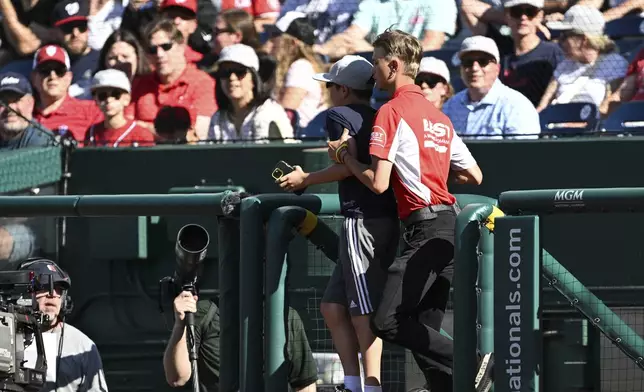 A young fan is ushered off the field during the third inning of a baseball game between the Washington Nationals and the Tampa Bay Rays, Saturday, Aug. 30, 2025, in Washington. (AP Photo/Terrance Williams)