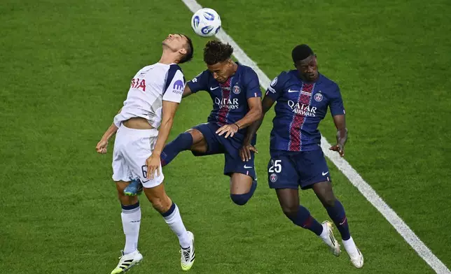 PSG's Desire Doue, center, jumps for a header with Tottenham's Joao Palhinha, left, and PSG's Nuno Mendes during the UEFA Super Cup soccer match between Paris Saint-Germain and Tottenham Hotspur in Udine, Italy, Wednesday, Aug. 13, 2025. (AP Photo/Denes Erdos)