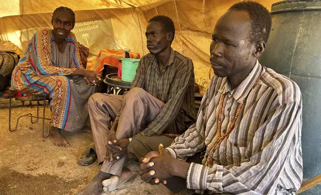 Daud Mahmoud Abdullah, 60, who says he spent six months in prison after being accused of cooperating with the Rapid Support Forces, sits with his wife and brother, whom he was reunited with at the Renk transit center, South Sudan, Saturday, Aug 9, 2025. (AP Photo/Adlai Coleman)