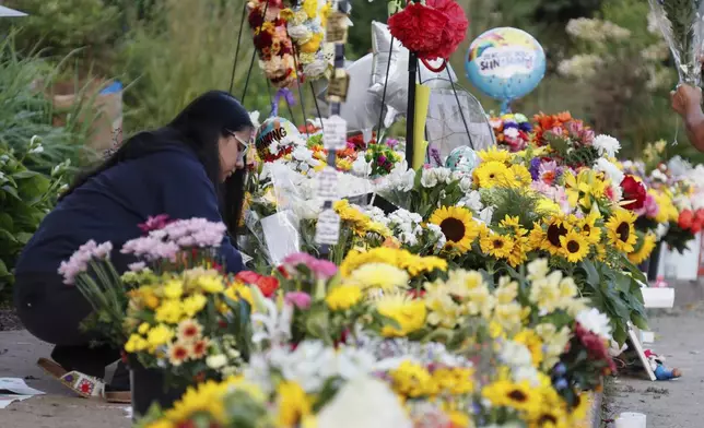 People visit a make-shift memorial at Annunciation Catholic Church after the Wednesday's shooting at the school, Friday, Aug. 29, 2025, in Minneapolis. (AP Photo/Bruce Kluckhohn)