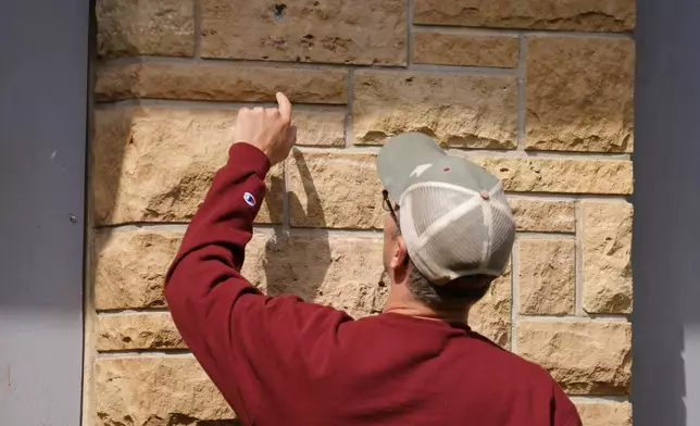 A man looks at the holes in the walls outside Annunciation Catholic Church after the Wednesday's shooting at the school, Friday, Aug. 29, 2025, in Minneapolis. (AP Photo/Bruce Kluckhohn)