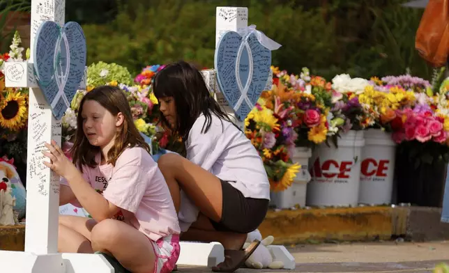 People visit a make-shift memorial at Annunciation Catholic Church after the Wednesday's shooting at the school, Friday, Aug. 29, 2025, in Minneapolis. (AP Photo/Bruce Kluckhohn)