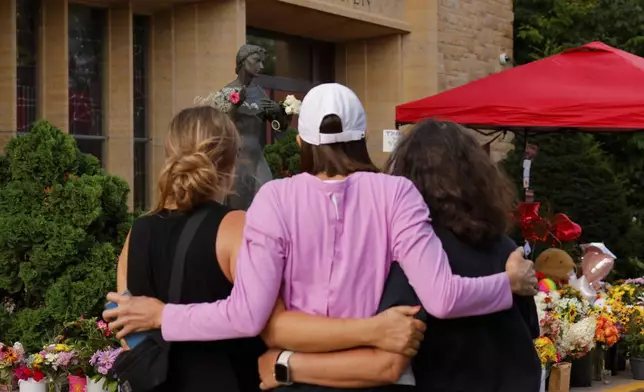 People visit a make-shift memorial at Annunciation Catholic Church after the Wednesday's shooting at the school, Friday, Aug. 29, 2025, in Minneapolis. (AP Photo/Bruce Kluckhohn)