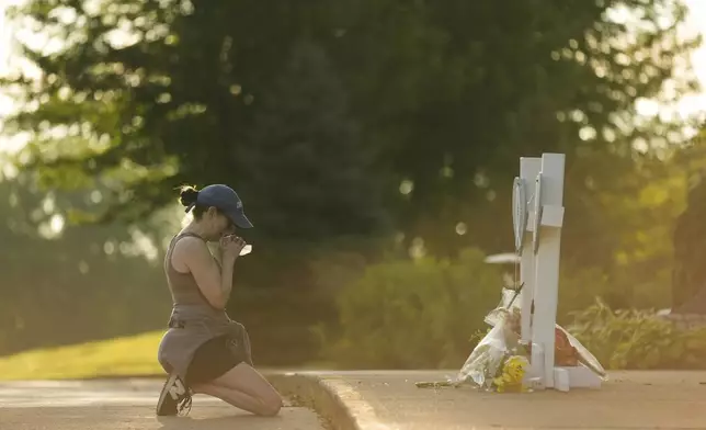 A person prays as she visits at a memorial at Annunciation Catholic Church after Wednesday's school shooting, Thursday, Aug. 28, 2025, in Minneapolis. (AP Photo/Abbie Parr)