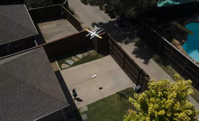 Julep Toth, 9, looks at a drone as it arrives at her house with a delivery, Thursday, July 31, 2025, in Frisco, Texas. (AP Photo/Julio Cortez)