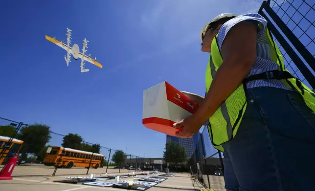 Masslie Arias, of DoorDash, prepares to load a delivery package on a hovering drone Thursday, July 31, 2025, in Frisco, Texas. (AP Photo/Julio Cortez)