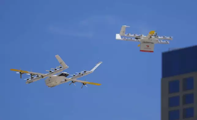 A drone, left, lands at a helipad as another lifts off with a DoorDash order, Thursday, July 31, 2025, in Frisco, Texas. (AP Photo/Julio Cortez)