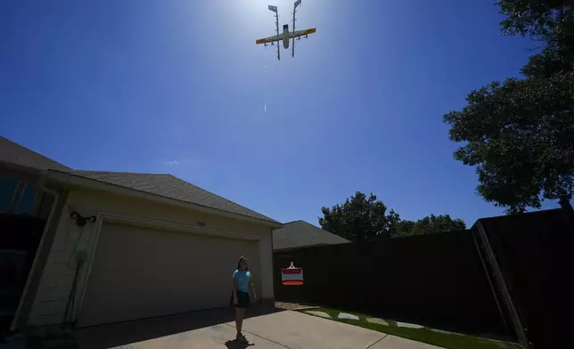 Julep Toth, 9, waits for a drone to drop off a delivery at her house, Thursday, July 31, 2025, in Frisco, Texas. (AP Photo/Julio Cortez)