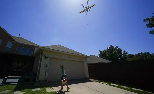 julep Toth, 9, carries a package delivered to her house via a drone, Thursday, July 31, 2025, in Frisco, Texas. (AP Photo/Julio Cortez)