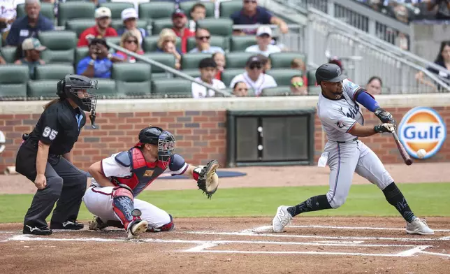 Home plate umpire Jen Pawol, left, watches Miami Marlins' Xavier Edwards, right, swing at a pitch in the first inning of a baseball game against the Atlanta Braves, Sunday, Aug. 10, 2025, in Atlanta. (AP Photo/Colin Hubbard)