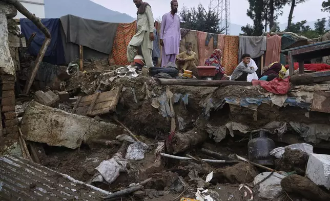 A villager Mateen Khan, center in white beard, and his family members sit over the rubble of their damaged home following Friday's flash flooding at a neighbourhood of Pir Baba, an area of Buner district, in Pakistan's northwest, Sunday, Aug. 17, 2025. (AP Photo/Muhammad Sajjad)