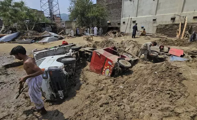 Local residents remove mud to recover vehicles from debris after Friday's flash flooding, in Mingora, the main town of Swat Valley, in Pakistan's northwest, Saturday, Aug. 16, 2025. (AP Photo/Sherin Zada)
