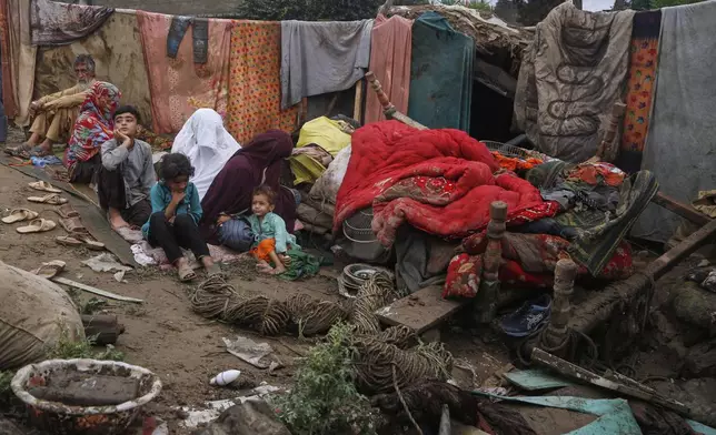 A villager Mateen Khan, left, and his family members sit over the rubble of their damaged home following Friday's flash flooding at a neighbourhood of Pir Baba, an area of Buner district, in Pakistan's northwest, Sunday, Aug. 17, 2025. (AP Photo/Muhammad Sajjad)
