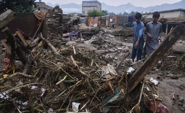 Villagers collect usable items through the rubble of their partially damaged home following Friday's flash flooding at a neighbourhood of Pir Baba, an area of Buner district, in Pakistan's northwest, Sunday, Aug. 17, 2025. (AP Photo/Muhammad Sajjad)